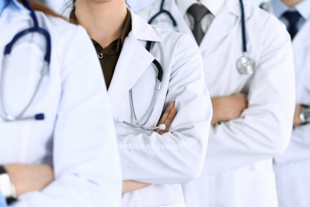 Group of modern doctors standing as a team with arms crossed in hospital office. Physicians ready to examine and help patients. Medical help, insurance in health care, best desease treatment and medicine concept.
